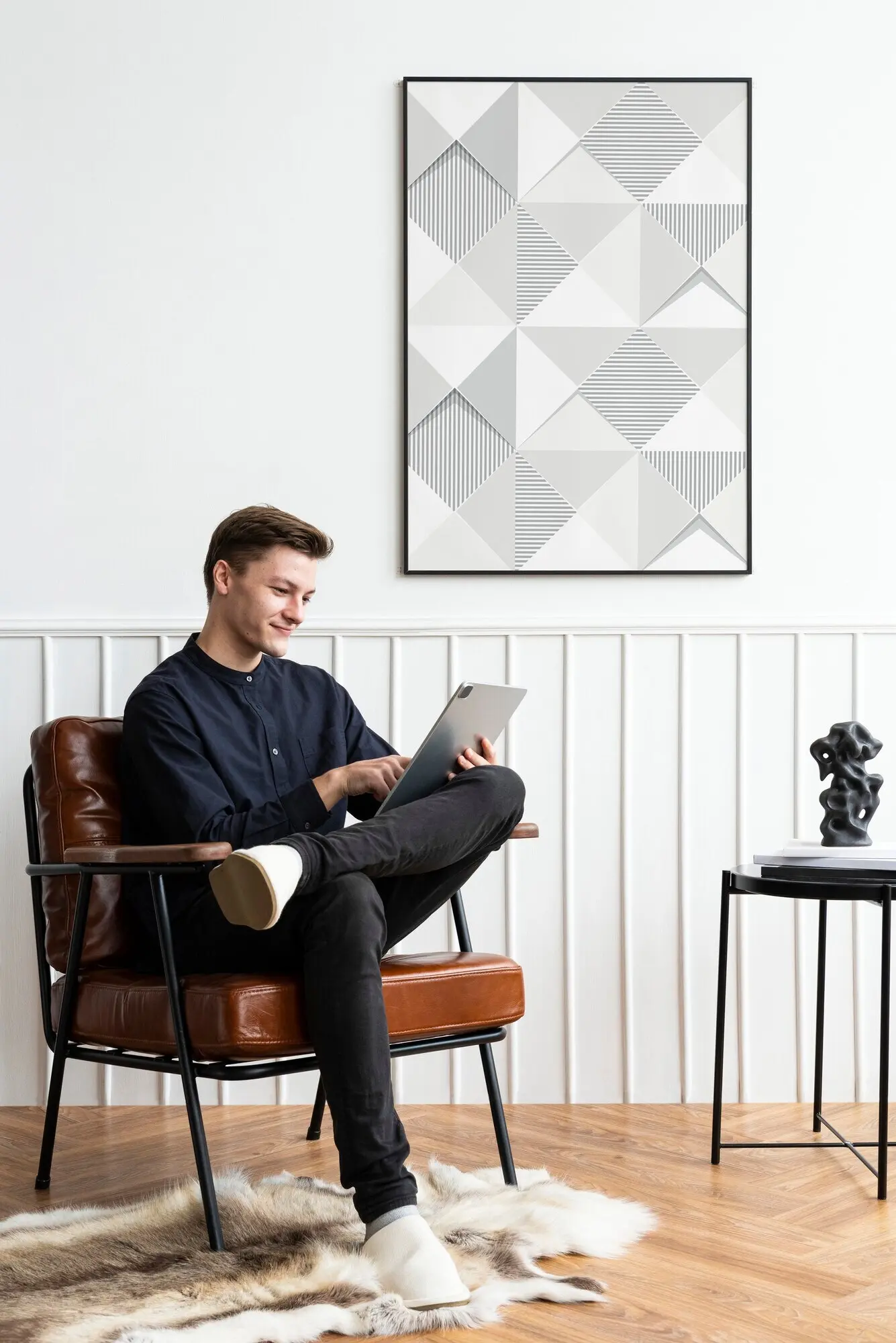 Ein Mann schaut in seinem Wohnzimmer auf sein Tablet.